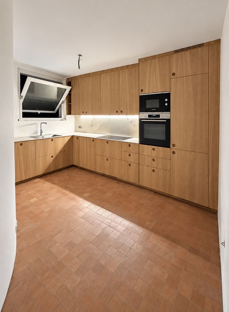 Cuisine en chêne à poignées rondes, plan et crédence blancs veinés, colonne four et micro-ondes encastrés, sol en tomettes